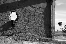 A black-and-white photo of a child playing in the ruins of a building in Afghanistan