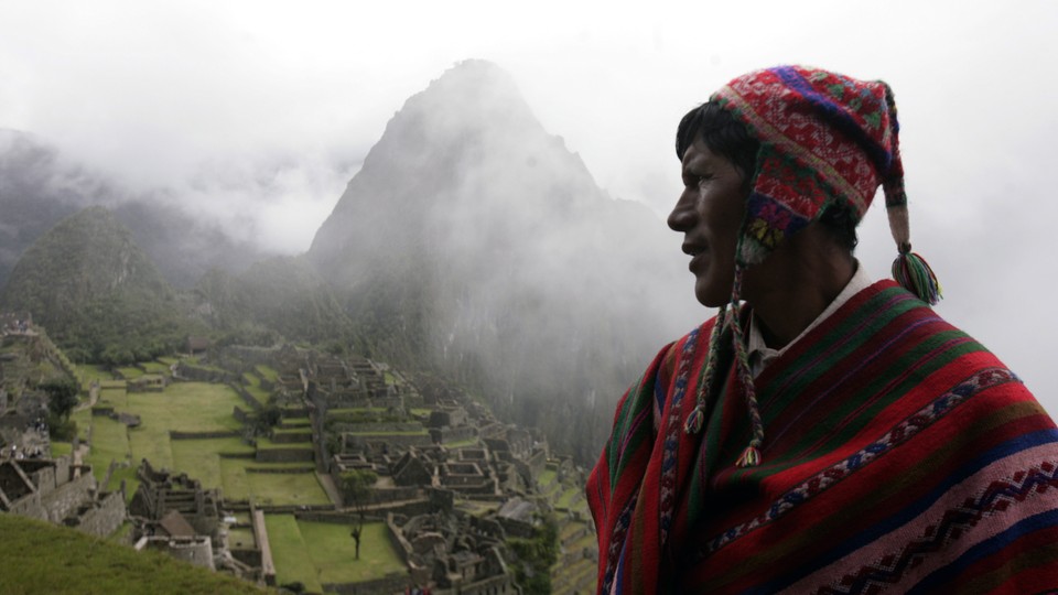 A Quechua musician stands next to the Machu Picchu.