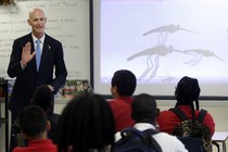 Florida Governor Rick Scott talks with students who are studying the Zika virus, while visiting a classroom on the first day of school, at the Jose de Diego Middle School, on August 22, 2016.