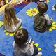 A photo of kids sitting on a carpet in a classroom.