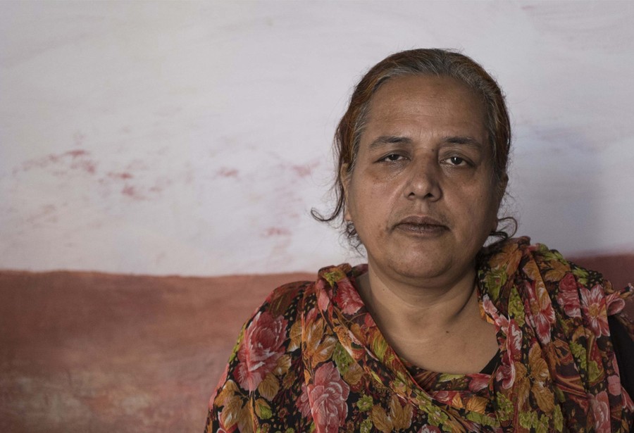 A photograph of the woman from the previous image, looking much older, sitting alone.
