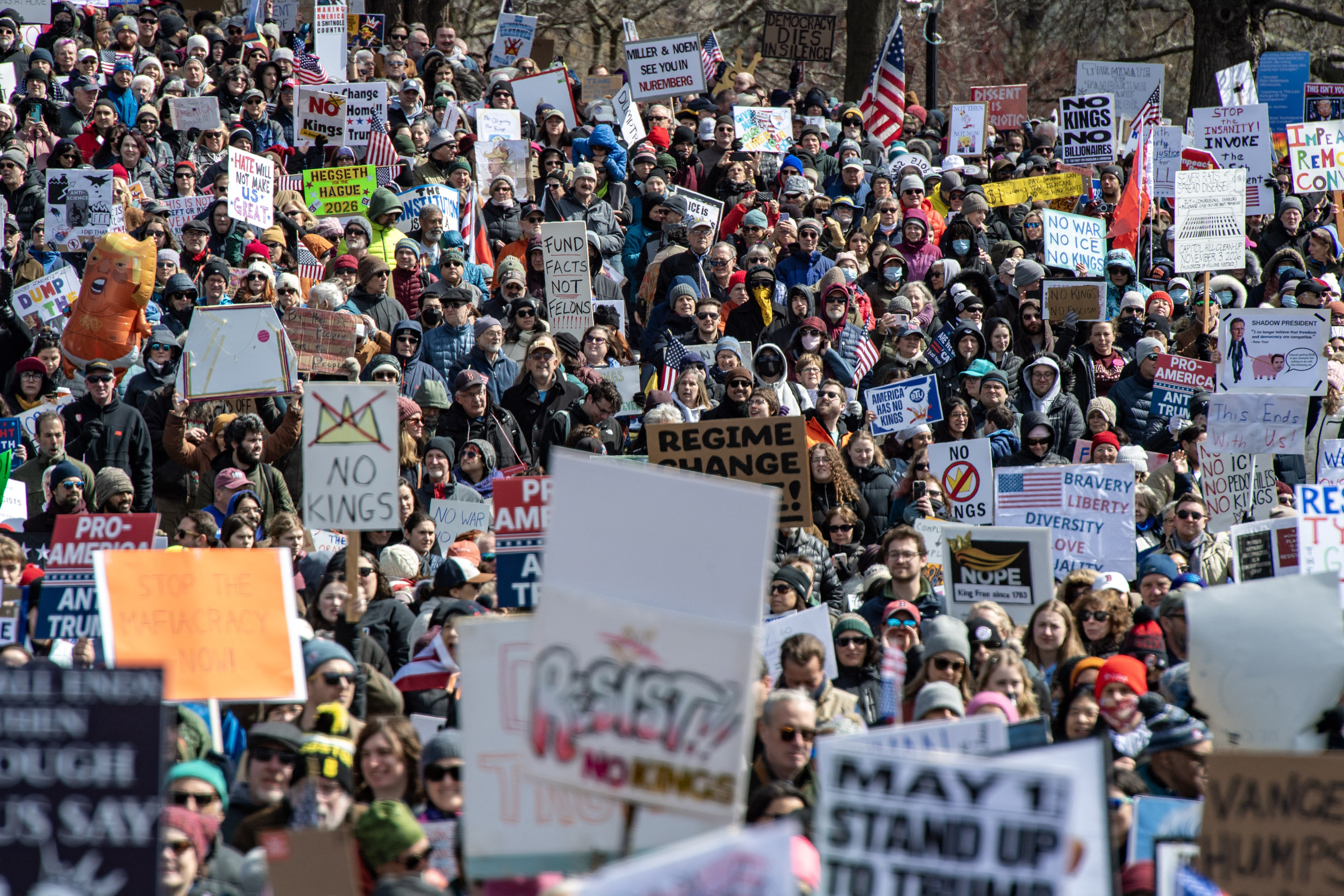 A large crowd of protesters, most holding American flags or anti-Trump signs