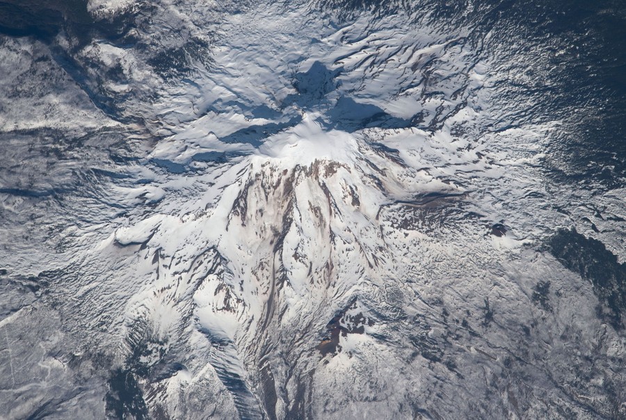 An aerial view of a large snow-covered volcano.