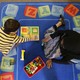 An overhead shot of a child playing with blocks on a blue carpet with an adult.