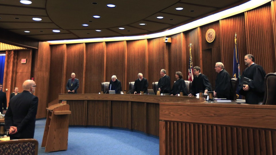 Justices in robes stand in a courtroom. 