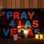 A poster next to flowers and candles reads, "Pray 4 Las Vegas"