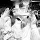 A black-and-white image of brides in wedding dresses scrambling onto a large structural wedding display