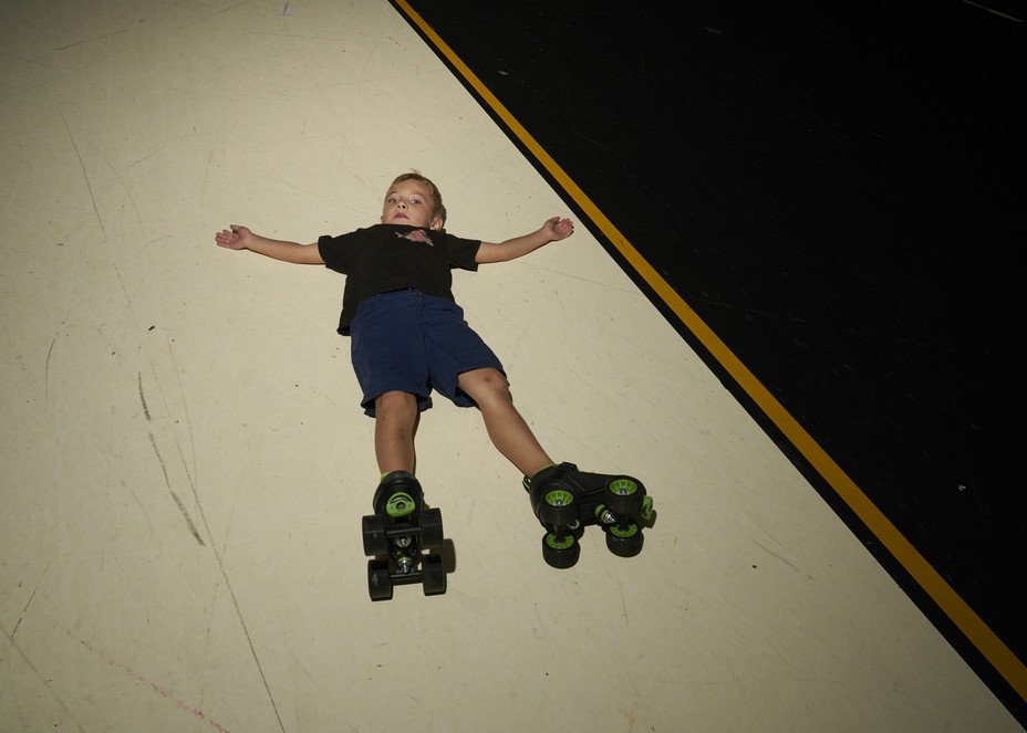 a kid lays flat out with skates on