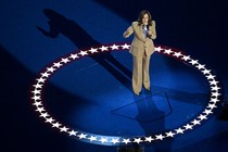 Kamala Harris speaking to microphone, standing in the middle of a circle of stars