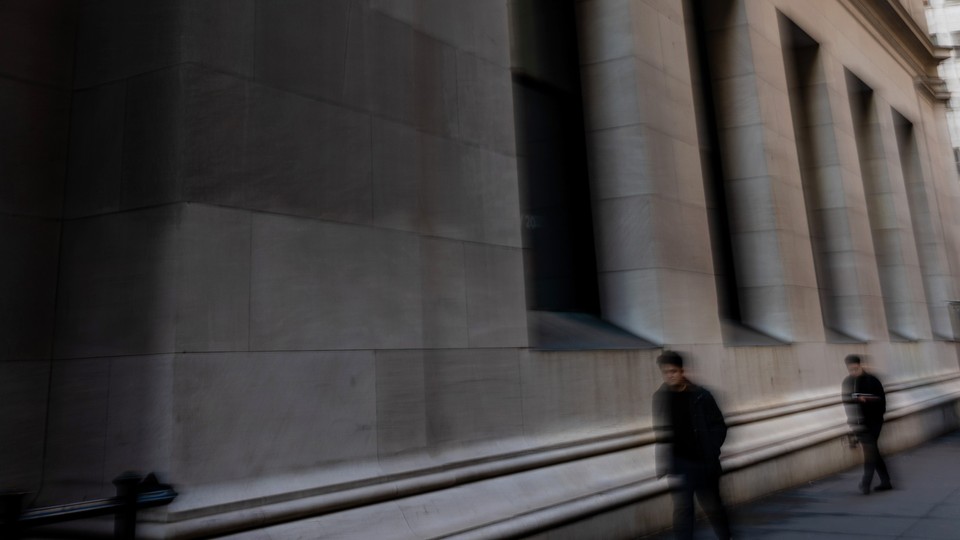 A blurry color photograph of a couple men walking down Wall Street.
