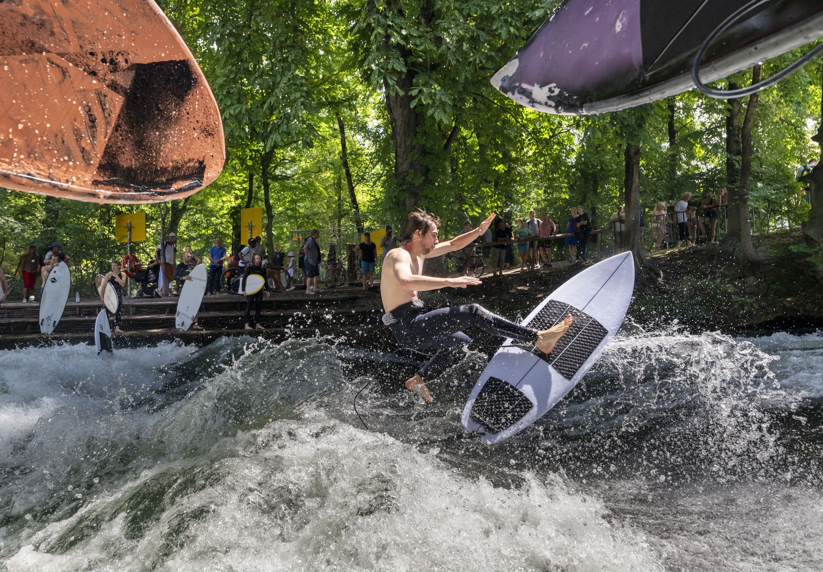 A man jumps with his surfboard on an artificial wave.