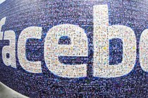 A wide-angle photograph of a wall plastered with the Facebook logo made of smaller photos