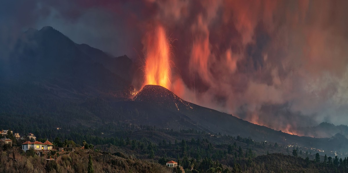Wide view of an erupting volcano situated on the side of a mountain