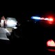 A photo of a police car behind a car that was pulled over at night