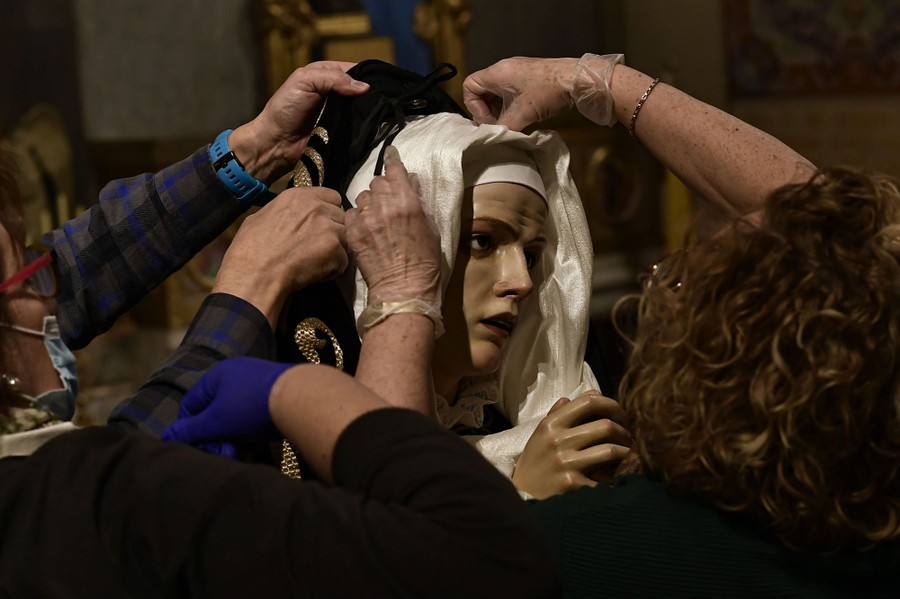 A group of people work on a statue of the Virgin Mary.