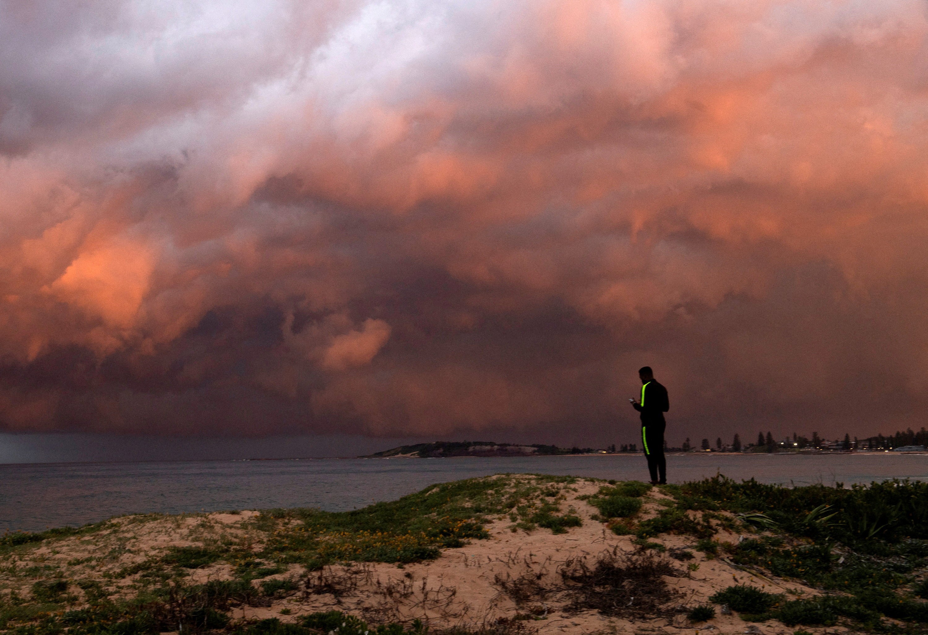 A man watches a storm sweep across a harbor.