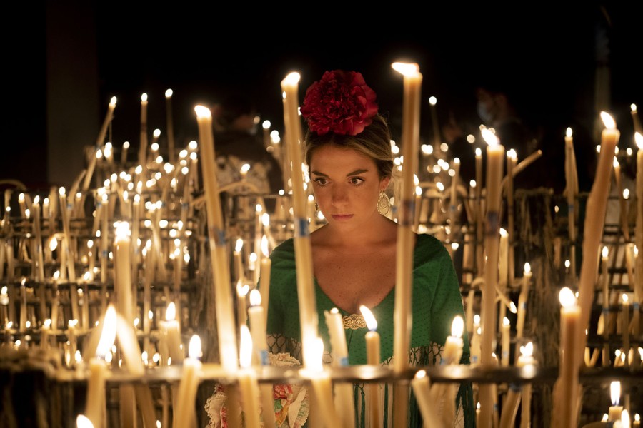 A person stands among dozens of lit candles.