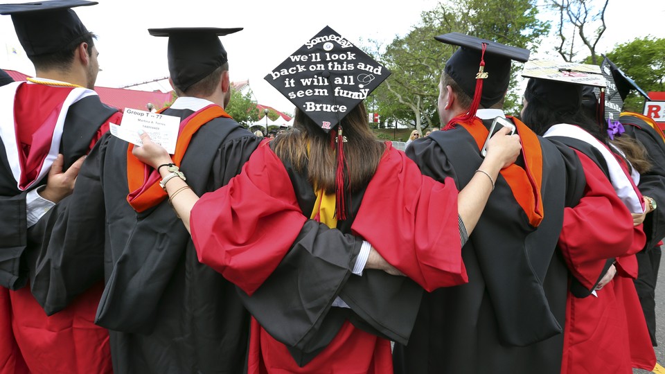 Graduates embrace in caps and gowns at commencement 