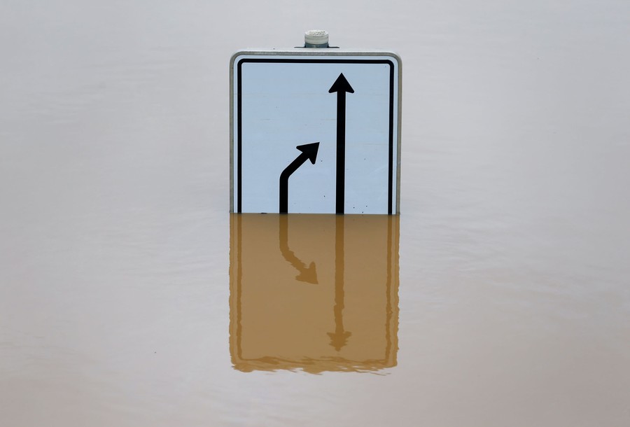 A road sign sits in a flooded street.