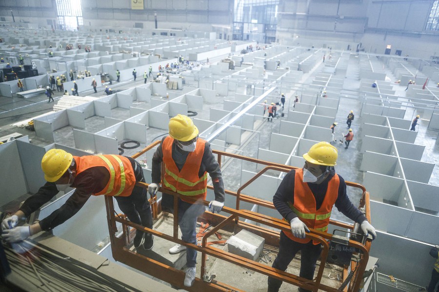 Employees work on a makeshift hospital that has rows and rows of cubicles.