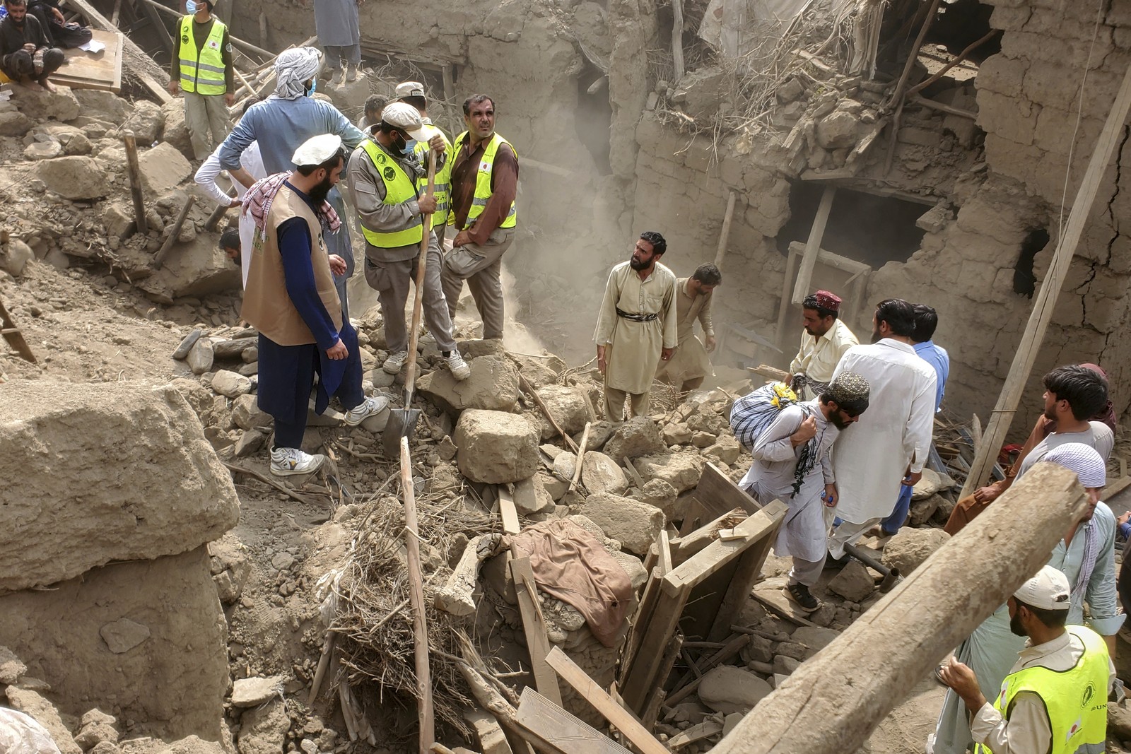 Workers and volunteers search through the rubble of a destroyed house.