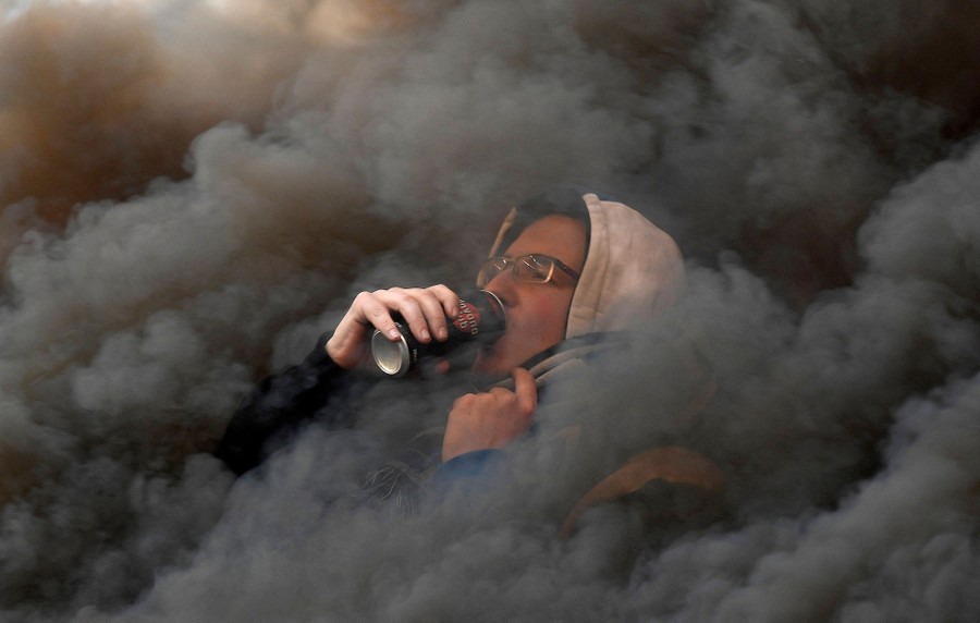 A sports fan in a stadium is engulfed in smoke from flares.