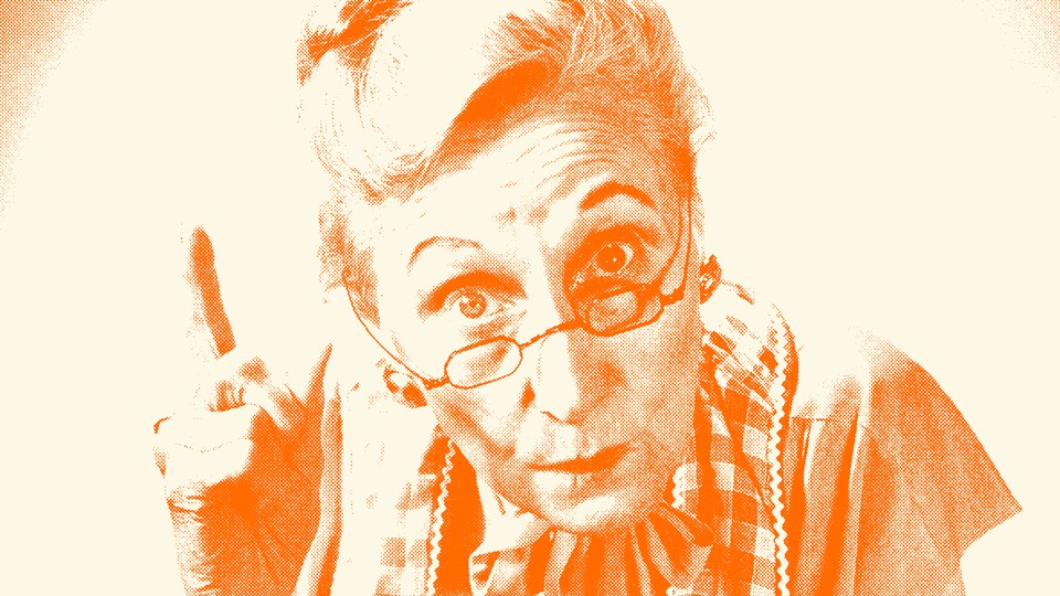 An older woman wearing glasses wags her finger