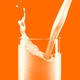An orange-tinted photo-illustration of milk being poured into a glass