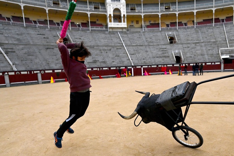 A person jumps up to stab a mock bull inside an empty bullring.