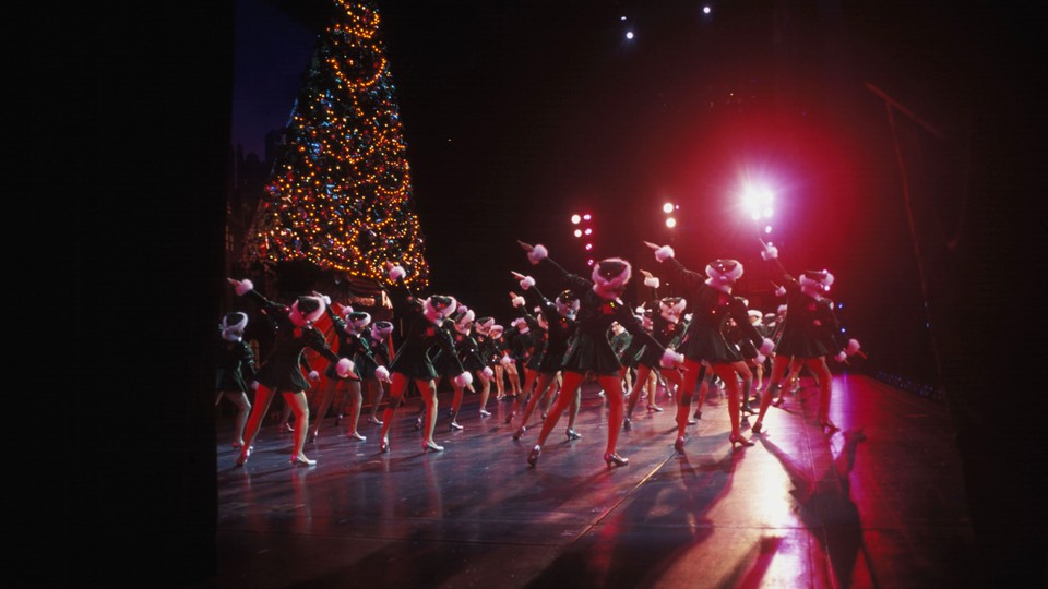 The Radio City Rockettes performing at Radio City Music Hall in front of a Christmas tree