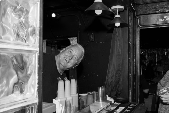 man stick his head out of a bar window