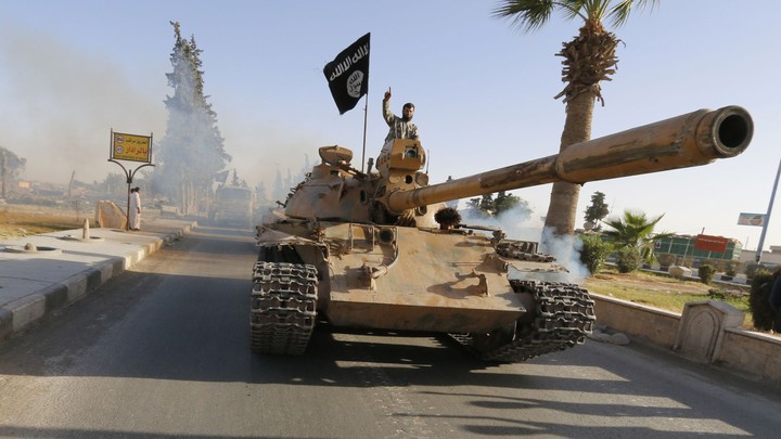 Militant Islamist fighters on a tank take part in a military parade along the streets of northern Raqqa province June 30, 2014.