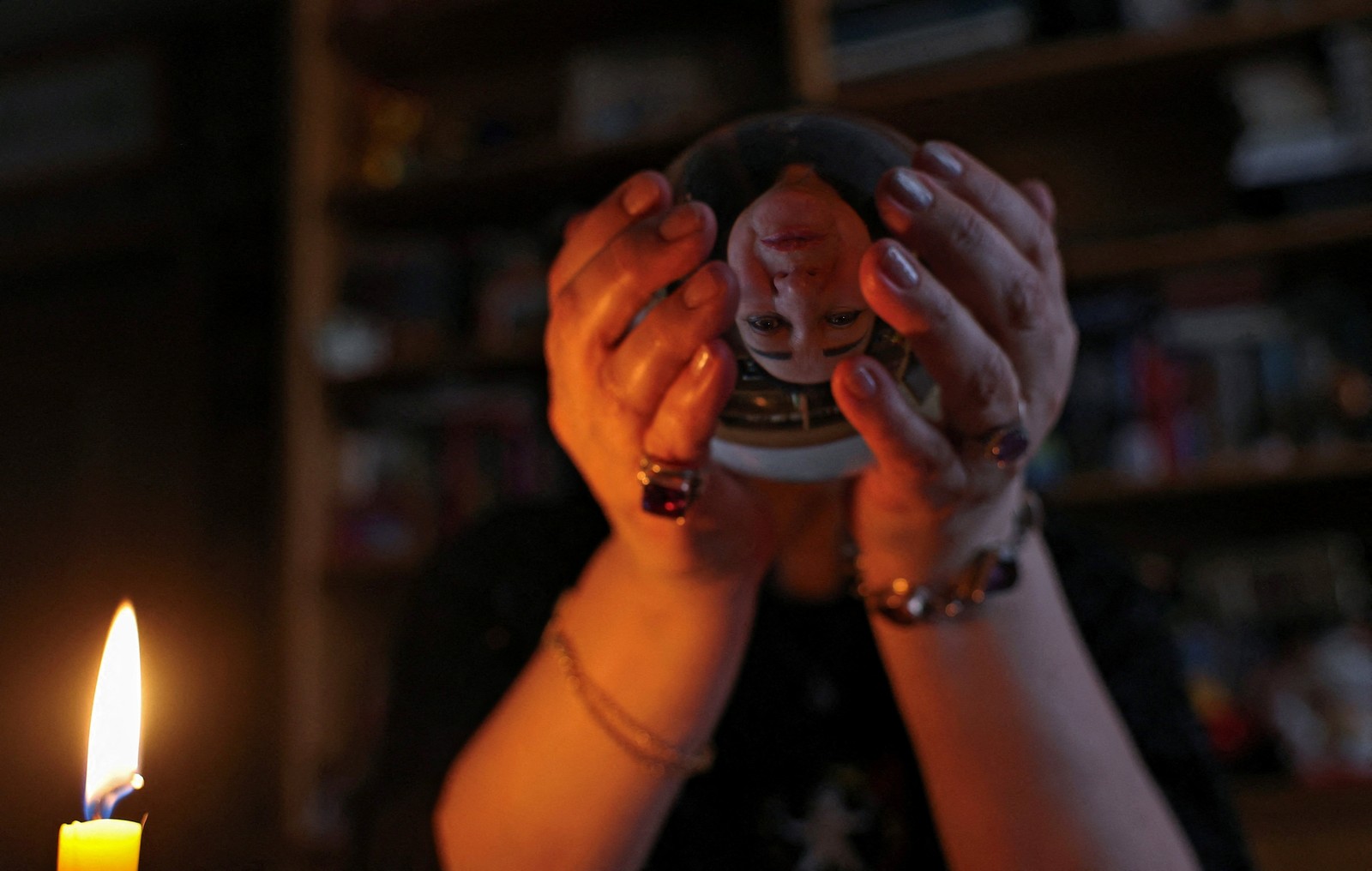A person holds a crystal ball in front of them, with their face seen, inverted, through the ball.