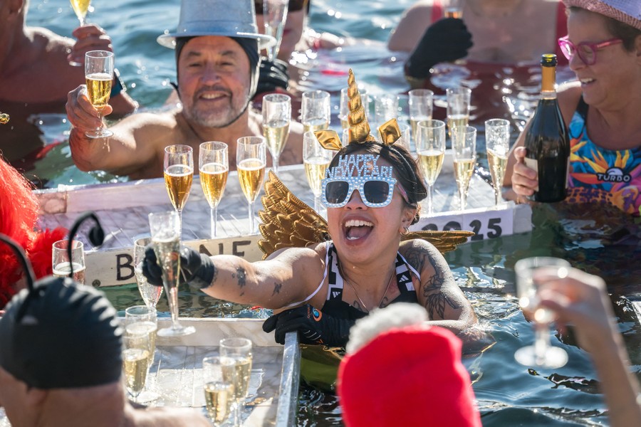 A group of swimmers in party hats drink champagne together.