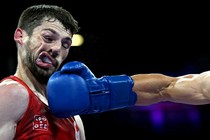 A boxer's contorted face, seen just after being punched hard, with his opponent's arm and glove below