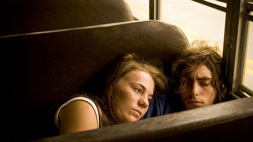 Two teens cuddle on a bus
