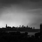 Black-and-white photo of Chicago's skyline in the distance, framed by other buildings in the foreground