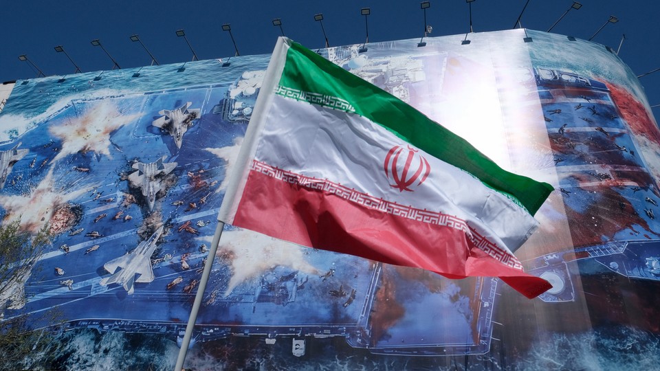 Iranian flag in the foreground with images of fighter jets in the background