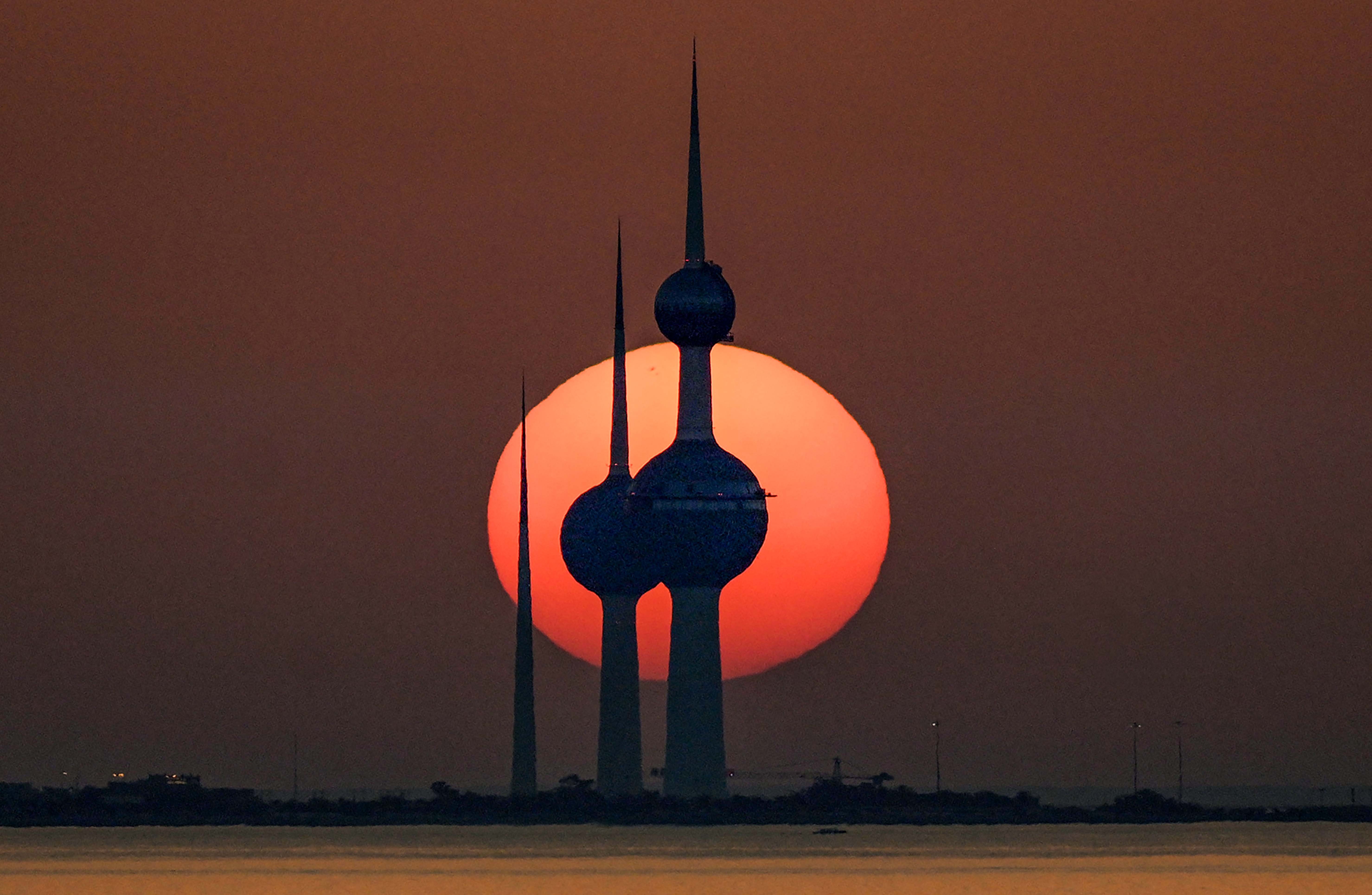 A sunset, seen beyond several tall distinctive towers