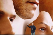 Phil Schiller stands in front of a screen displaying images of disembodied faces.