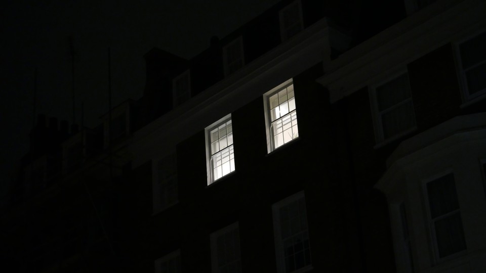Two lit windows in a home, as seen from across the street