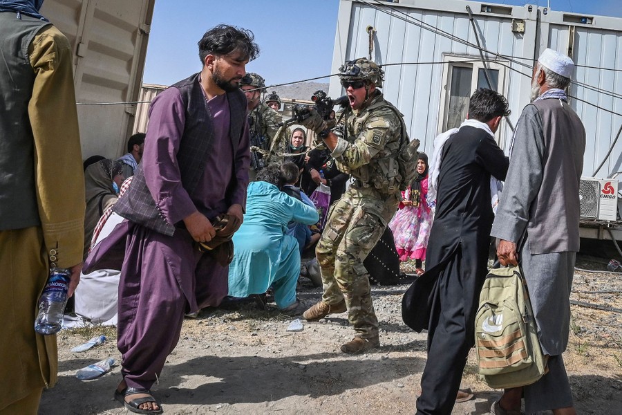 A U.S. soldier brandishes his weapon amid a crowd of Afghan people.