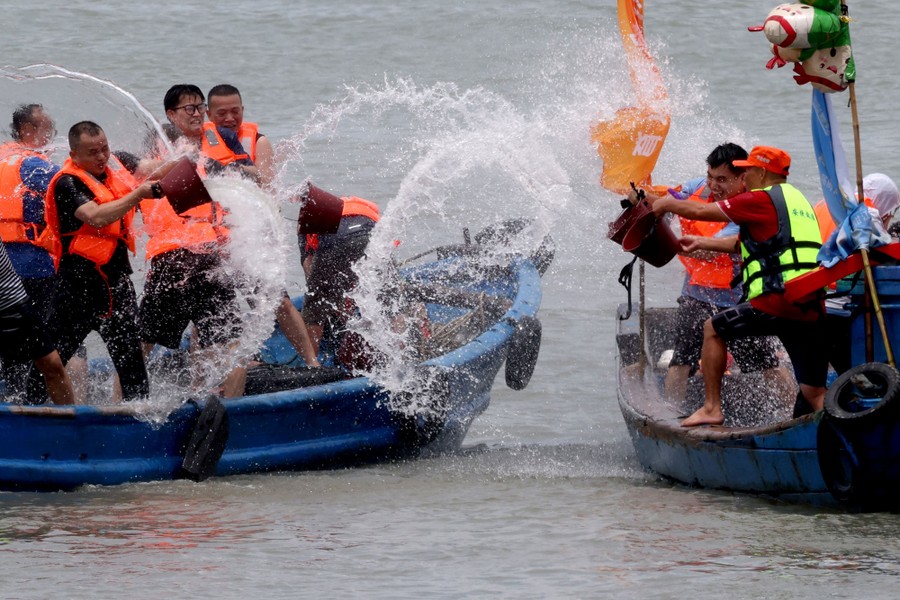 People in two small boats splash each other using buckets.