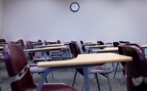 An empty classroom with desks and a clock on the wall