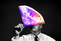 A man in black and white holding up a ring topped with a giant colorful diamond