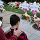 A man places his hand on the back of a boy while standing in front of a memorial.
