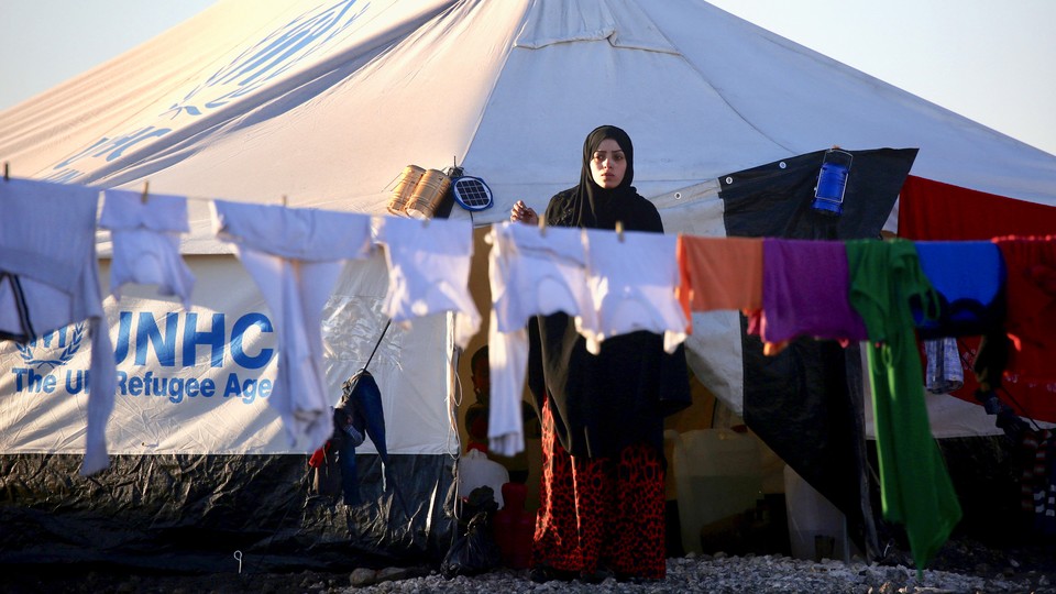 A woman hangs laundry at a refugee camp in Syria in March 2017.
