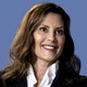 A photo of Gretchen Whitmer smiling against a blue background