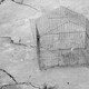 A metal cage sits on cracked, dry ground