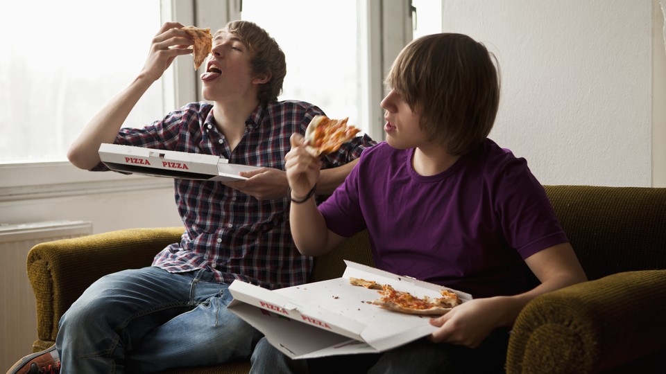 Two teenage boys eating pizza